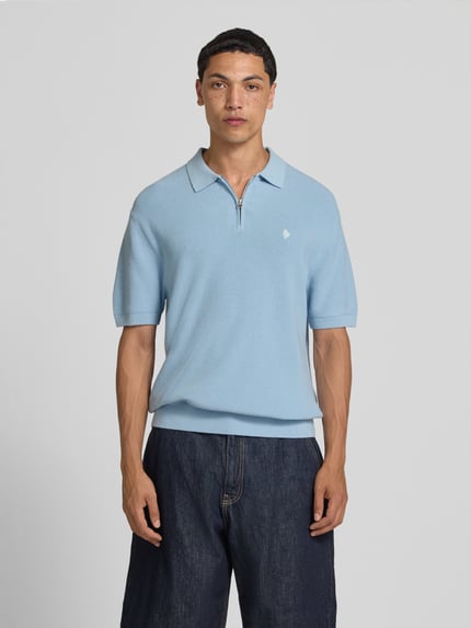Männermodel trägt lichtblauw Boxy Fit Poloshirt mit Logo-Stitching van REVIEW, puur katoen, polokraag, korte ritssluiting, ruglengte maat M 67 cm, Ganzkörperansicht von vorne