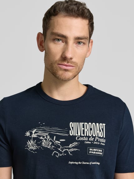 Męski model nosi Regular Fit T-Shirt aus reiner Baumwolle von s.Oliver RED LABEL, efekt: jednolity kolor, krój regular fit, nadruk z motywem, rękaw: krótki rękaw, bawełna, nahaufnahme oberkörper.