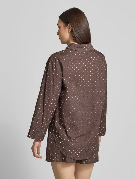 Frauenmodel trägt Relaxed Fit Bluse im Allover-Look Modell 'FRIDA' von Noisy May in Braun mit weißen Punkten, Material-Mix, Hemdblusenkragen, Brusttasche, Label-Detail, Rückenlänge 76 cm, Ärmellänge 52 cm, Ganzkörperansicht Rückansicht.