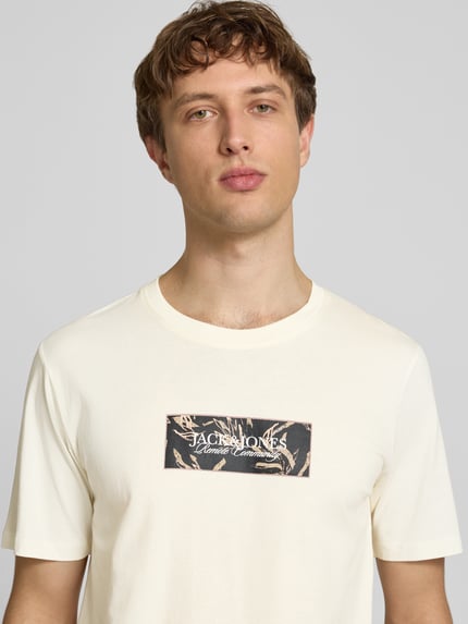 Mannenmodel draagt T-shirt met labelprint van Jack & Jones in crème, puur katoen, recht model, ronde hals, ruglengte maat M 67 cm, Nahaufnahme Oberkörper.