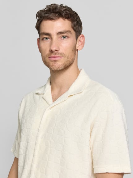 Männermodel trägt Regular Fit Freizeithemd mit Strukturmuster von MCNEAL in Creme mit Reverskragen, Nahaufnahme Oberkörper. Baumwoll-Mix, sichtbare Knopfleiste, feine Struktur.