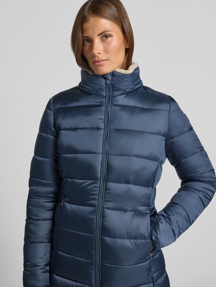Frauenmodel trägt Steppmantel mit abnehmbarer Kapuze Modell 'CLELIA' von Save The Duck in Blau, glatte Oberfläche, Nahaufnahme Oberkörper.
