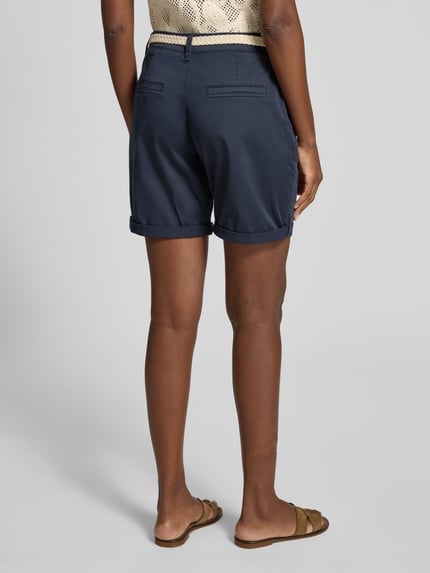 Vrouwenmodel draagt Regular Fit Bermudas uit katoenmix van s.Oliver RED LABEL in effen marineblauw, riemlussen, omslag, steek- en achterzakken, twillstructuur. Volledige lichaamsweergave achterkant.