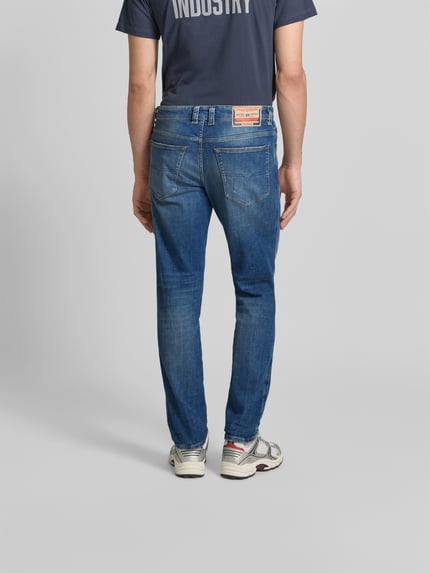 Mężczyzna nosi Straight Fit Jeans aus Baumwoll-Mix von Diesel, mieszanka bawełny i elastanu, 5 kieszeni, detal z logo, długość wewnętrzna nogawki 80 cm, szerokość w rozmiarze 32: 45 cm, widok całej sylwetki z tyłu.