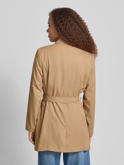 Frauenmodel trägt Regular Fit Trenchcoat mit doppelreihiger Knopfleiste Modell 'VALERIE' von ONLY, Optik: Unifarben, Umlegekragen, Taillengürtel, Langarm, seitliche Eingrifftaschen, Ganzkörperansicht Rückansicht.