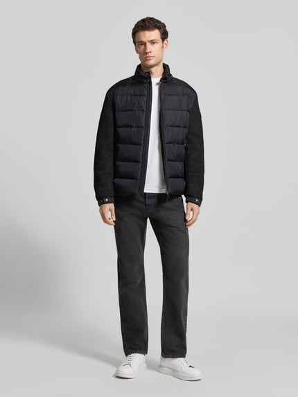 Männermodel trägt Regular Fit Steppjacke mit Stehkragen Modell 'Ciscos' von JOOP! COLLECTION in Schwarz, Ganzkörperansicht von vorne.