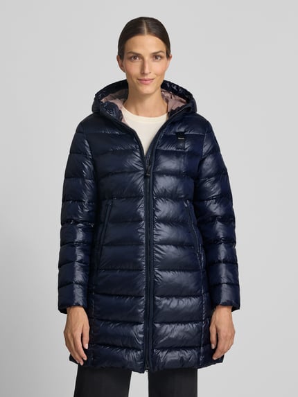 Vrouwenmodel draagt lange jas in Stiksels, regular fit, Capuchon met tunnelkoord, Steekzakken met ritssluiting, Model 'Adelaide' van Blauer USA, Ruglengte maat S 85 cm, Schouderbreedte 40 cm, Borstwijdte 48 cm, Mouwlengte 62 cm, Logo-design, Ganzlichaamsvooraanzicht