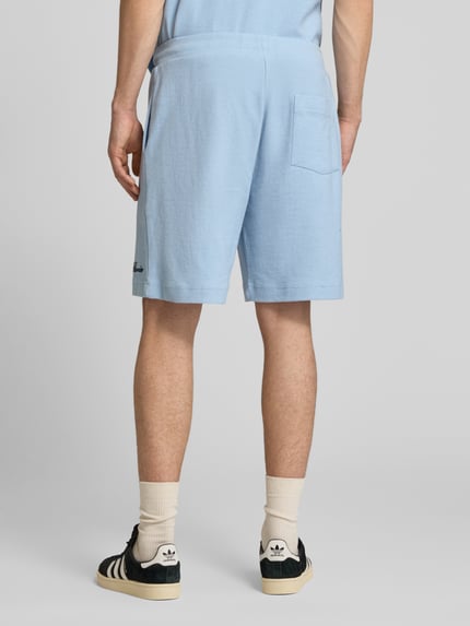 Männermodel trägt Shorts mit Label-Stitching von REVIEW in Hellblau mit Strukturmuster, Regular-Fit aus Baumwoll-Mix, Ganzkörperansicht Rückansicht.