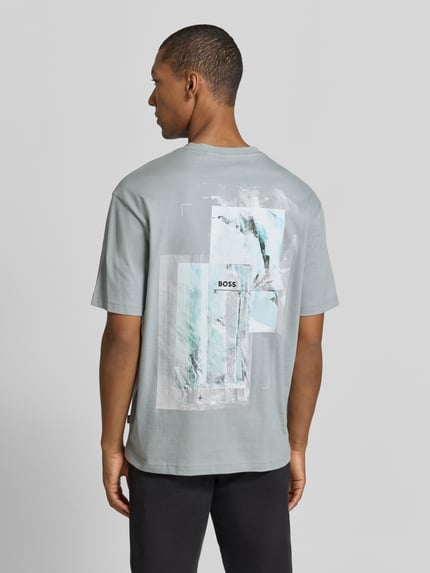 Männermodel trägt Regular Fit T-Shirt aus reiner Baumwolle Modell 'Te_Frame' von BOSS, abstraktes Print-Design in Grautönen, Ganzkörperansicht Rückansicht, Herren T-Shirt von BOSS Orange.