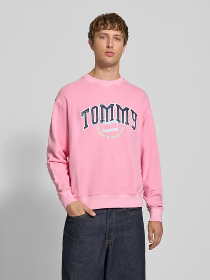 Männermodel trägt Relaxed Fit Sweatshirt aus reiner katoen van Tommy Jeans in roze met ronde hals, zachte textuur, Ganzkörperansicht von vorne, Heren sweatshirt.