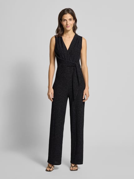 Modelka kobieca nosi szimmernder Jumpsuit mit V-Ausschnitt od Rich & Royal, czarny połysk, regular fit, pasek w talii, zdjęcie całej sylwetki z przodu. Materiał miks ze stretchem, długość pleców 74 cm, szerokość biustu 39 cm, całkowita długość 150 cm, długość nogawki 89 cm.