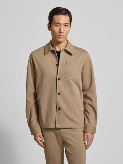 Männermodel trägt Hemdjacke mit Knopfleiste von Lindbergh in Beige, Regular Fit, Kentkragen, Brust- und Eingrifftaschen, Ganzkörperansicht von vorne.
