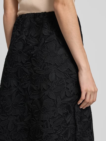 Kobiece model prezentuje spódnica midi z koronki w linii a od Milano Italy, szerokość w rozmiarze 36: 37 cm, całkowita długość 87 cm, elastyczny pas, zbliżenie na biodra
