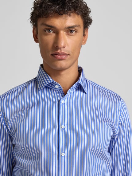 Männermodel trägt Slim Fit Business Hemd aus Baumwolle mit Kentkragen von SEIDENSTICKER, blauer Streifen-Look, Nahaufnahme Oberkörper. Rückenlänge 77 cm, Schulterbreite 42 cm, Ärmellänge 65 cm, Größe 40, Knopfleiste.