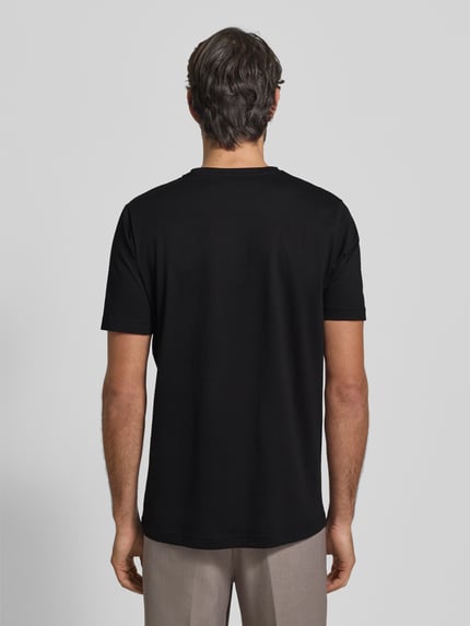 Männermodel trägt T-Shirt mit Logo-Print von Fynch-Hatton, reine Baumwolle, schwarzer Stoff, gerader Schnitt, Ganzkörperansicht Rückansicht.
