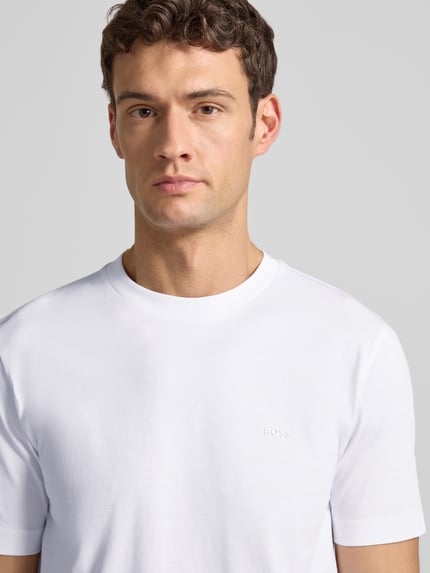 Männermodel trägt T-Shirt aus Baumwolle Modell 'Thompson' von BOSS, gerade Passform, dezenter Logo-Print, Nahaufnahme Oberkörper.