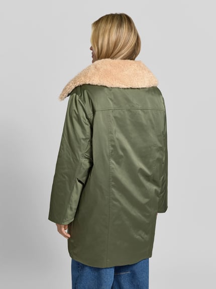 Frauenmodel trägt Daunenjacke mit Webpelzkragen Modell 'DAIMI' von BAUM & PFERDGARTEN, oliv, glänzende unifarbene Struktur, Longline, Ganzkörperansicht Rückansicht.