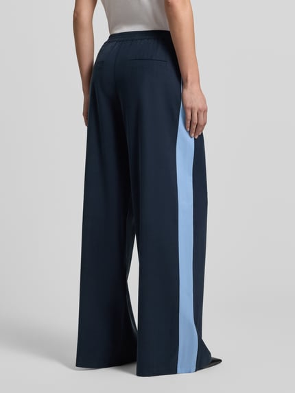 Frauenmodel trägt Fließende Viskose-Hose mit Kontraststreifen - curated by Tinvcb von SIC, weites Bein, elastischer Bund, Rückansicht.