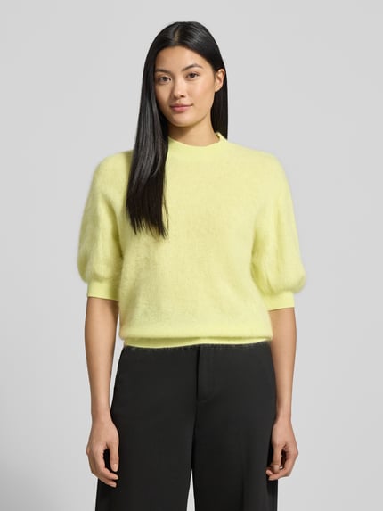 Modelka kobieca nosi Strickpullover aus Wolle mit 1/2-Arm od Herzensangelegenheit, kolor jasnożółty, regular fit, okrągły dekolt, widok całej sylwetki z przodu.