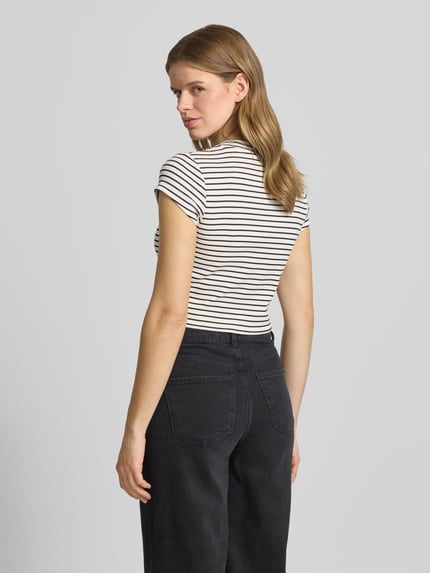 Kobiece model prezentuje Cropped T-Shirt mit Streifenmuster und Logo od Calvin Klein Jeans, mieszanka bawełny i elastanu, wzór w paski, logo, krój krótki, okrągły dekolt, długość tyłu w rozmiarze S: 39 cm, całkowity widok z tyłu.
