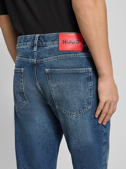 Männermodel draagt Relaxed Fit Jeans uit puur katoen Model 'HUGO 838' van HUGO, look: effen, denim, labelpatch, 5-pocketmodel, detailopname rug.