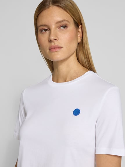 Vrouwenmodel draagt Regular Fit t-shirt uit puur katoen model 'LUALAA EMBRO' van Armedangels, look: effen, labelopschrift, ronde hals, korte mouw, fijnrib materiaalverwerking, Nahaufnahme bovenlichaam.