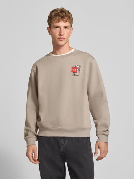 Männermodel trägt Relaxed Fit Sweatshirt aus Baumwoll-Mix mit Label-Detail von The North Face in Beige, elastische Abschlüsse, Ganzkörperansicht von vorne.
