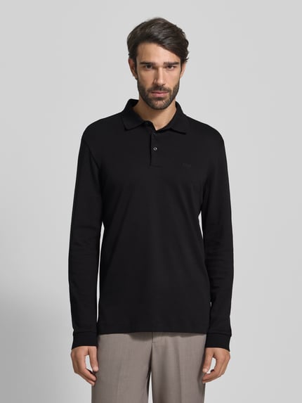 Męskimodel nosi koszulkę polo z napisem z logo Poloshirt mit Label-Schriftzug od BOSS, bawełna, prosty krój, kołnierzyk polo, model Pado 30, listwa guzikowa, fason z długim rękawem, prążkowane zakończenia rękawów, długość tyłu 76 cm w rozmiarze L, widok całej sylwetki z przodu.