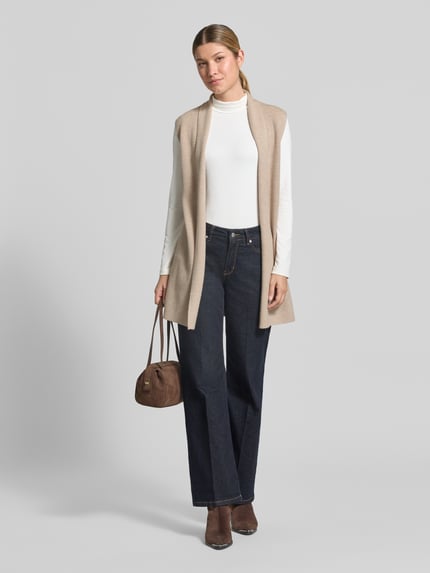 Frauenmodel trägt Strickweste aus Viskose-Mix mit offener Front von Christian Berg Woman, beige, Straight Fit, Feinripp, Jeans, Ganzkörperansicht von vorne.