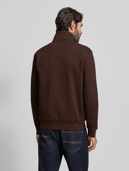 Männermodel trägt Regular Fit Troyer aus Baumwoll-Mix von Tommy Hilfiger in Dunkelbraun, unifarben, gerippte Abschlüsse, Ganzkörperansicht Rückansicht.
