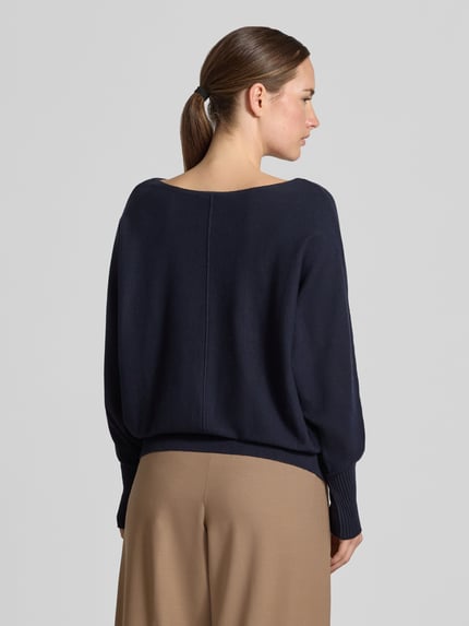 Młody modelka nosi sweter z dzianiny z mieszanki wiskozy od MORE, ciemnoniebieski, luźny krój, dekolt w łódkę, prążkowane ściągacze, ozdobny szew z przodu, casualowe wykończenia, długość tyłu w rozmiarze 36: 53 cm, długość rękawów: 62 cm, widok całej sylwetki od tyłu.