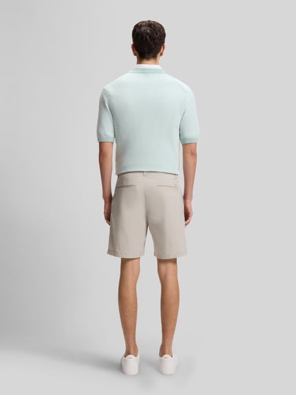 Männermodel trägt Regular Fit Chino-Shorts aus Baumwoll-Mix von BOSS Orange, efekt: jednolity kolor, krój regular fit, aplikacja z metką, szlufki na pasek, zapięcie na guzik i zamek błyskawiczny, tunel, wpuszczane kieszenie, kieszenie z tyłu, mieszanka bawełny, jasny kolor, gładka tekstura, Ganzkörperansicht Rückansicht.