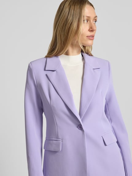 Frauenmodel trägt Slim Fit Blazer mit Pattentaschen Modell 'Isa' von GUIDO MARIA KRETSCHMER WOMAN aus Material-Mix mit Stretch-Anteil, Reverskragen, 1-Knopfverschluss, in zartem Flieder und glatter Struktur, Nahaufnahme Oberkörper.