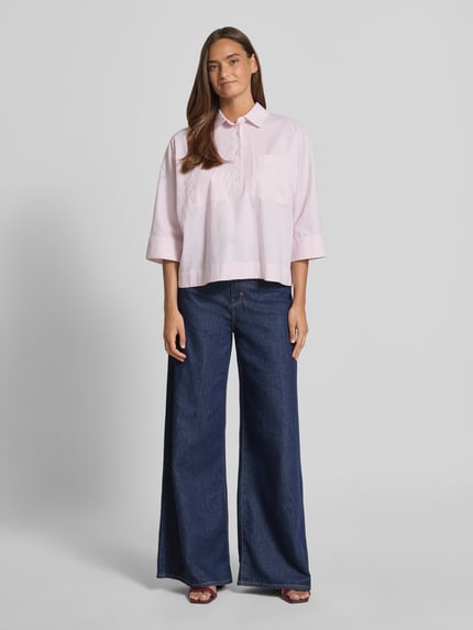 Frauenmodel trägt Regular Fit Bluse Umlegekragen Modell 'Fadessa' von OPUS aus Reine Baumwolle in zartem Rosa, 3/4-Arm, Ganzkörperansicht von vorne, Rückenlänge bei Größe 36: 60 cm, Ärmellänge 42 cm, strukturierte Oberfläche mit breiten Denim-Jeans.