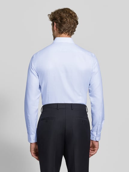 Männermodel trägt Slim Fit Businesshemd aus reiner Baumwolle von Jake*s in Hellblau, glatte Struktur, Ganzkörperansicht Rückansicht.