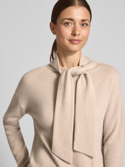 Frauenmodel trägt Kaschmirpullover mit Schal-Detail von Christian Berg Woman aus reinem Kaschmir in Beige mit gerippten Abschlüssen, Nahaufnahme Oberkörper.