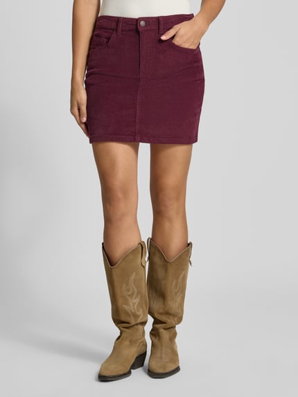 Vrouwenmodel draagt minirok uit katoenmix in corduroy look Model 'Yolanda' van NOISY MAY®, bordeaux, nauwsluitend, 5-pocketmodel, knoop- en ritssluiting, bandwijdte 39 cm, totale lengte 41 cm, voorkant hele lichaam