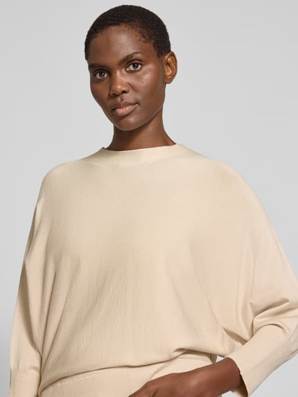 Frauenmodel trägt Oversized Pullover mit Fledermausärmeln von s.Oliver BLACK LABEL in Beige, Feinstrick, U-Boot-Ausschnitt, Nahaufnahme Oberkörper.