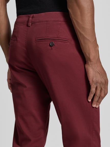 Männermodel trägt Slim Fit Chino aus Baumwoll-Mix Modell 'GABARDINE' von Selected in Dunkelrot, glatte Oberfläche, Nahaufnahme Rückansicht, Herren Chino.