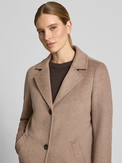 Frauenmodel trägt Regular Fit Mantel mit Woll-Anteil von s.Oliver RED LABEL in Beige mit Knopfleiste, weiche Textur, Nahaufnahme Oberkörper.