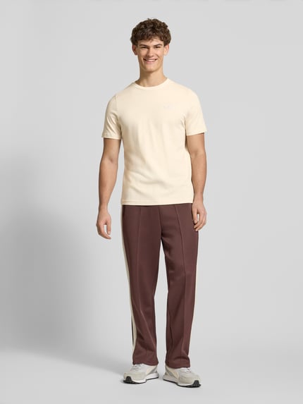 Männermodel trägt T-Shirt aus reiner Baumwolle von PUMA PERFORMANCE in Beige, gerader Schnitt, Rundhalsausschnitt, Ganzkörperansicht von vorne.