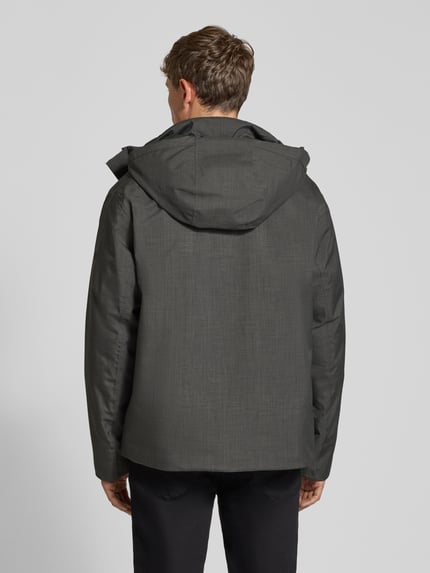 Männermodel trägt Jacke mit Kapuze und Pattentaschen Modell 'LAMOON' von JACK & JONES in dunklem Grau, strukturierte Optik, Ganzkörperansicht Rückansicht. Herren Jacke Regular Fit, verdeckter Reißverschluss.