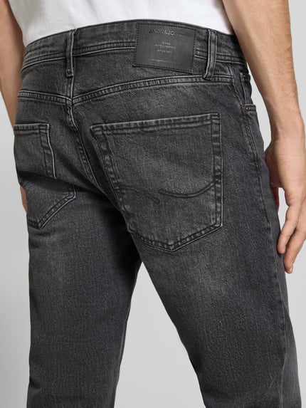 Männermodel trägt Regular Fit Straight Fit Jeans mit Label-Patch von JACK & JONES in dunklem Used Look Denim, Detailaufnahme Rückansicht.