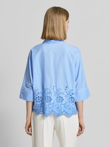 Frauenmodel trägt Boxy Fit Bluse mit Lochstickerei von Emily Van den Bergh in Hellblau, Reine Baumwolle, Hemdblusenkragen, Knopfleiste, Rückenlänge 54 cm, Ärmellänge 52 cm, Ganzkörperansicht Rückansicht.