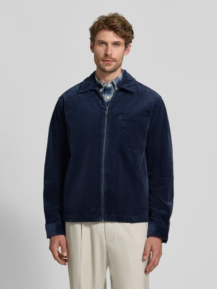Männermodel trägt Regular Fit Hemdjacke aus Cord mit Brusttasche von MCNEAL in Dunkelblau, Kentkragen, Reißverschluss, Ganzkörperansicht von vorne. Baumwoll-Elasthan-Mix, Rückenlänge bei Größe M 70 cm.