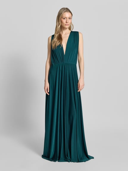 Kobiece modelka nosi Maxikleid mit tiefem V-Ausschnitt von Rose Avenue, kolor szmaragdowy, taliowany fason, tasiemka w talii, ramiączka krzyżowane z tyłu, długość tyłu 135 cm w rozmiarze S, gładka tekstura, pełen widok z przodu.