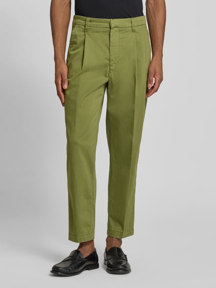 Mannelijk model draagt Regular Fit Chino uit katoenmix model 'TAAMIR PLEATED' van Armedangels, look: effen, regular fit pasvorm, katoenmix, met logostitching, riemlussen, schiebehakensluiting en verdekte ritssluiting, achterzakken, zijsteekzakken. Ganzkörperansicht van voren.