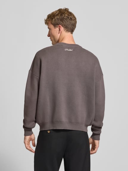 Mannermodel draagt Relaxed Fit gebreide pullover uit puur katoen van PROHIBITED in effen taupe met labelstitching, ribboorden, losse pasvorm, ruglengte maat M 64 cm, mouwlengte maat M 59 cm, Ganzkörperansicht Rückansicht.