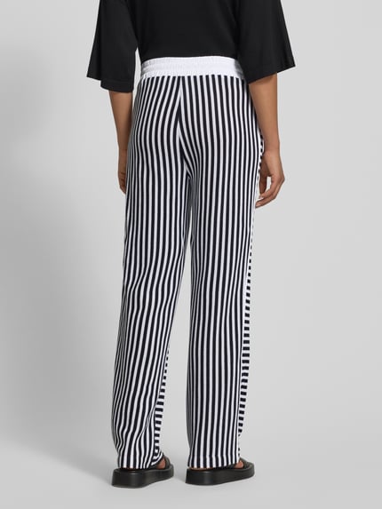 Vrouwenmodel draagt Hose im Allover-Look met elastische band en tunnelkoord van Marc Cain, puur katoen, relaxed fit, structuurpatroon, all-over look, zwart-witte strepen, binnenbeenlengte maat 36: 79 cm, bandwijdte maat 36: 38 cm, geheel lichaam achteraanzicht.