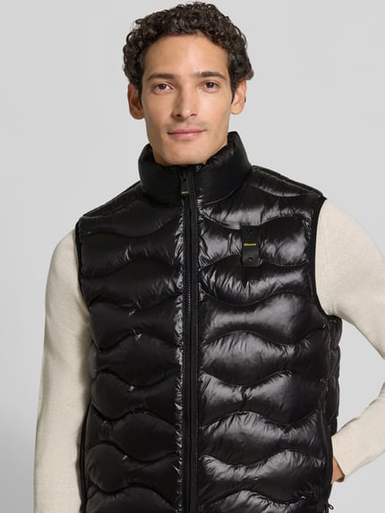 Männermodel trägt glänzende, schwarze Steppweste mit Zweiwege-Reißverschluss Modell 'DANNY' von Blauer USA, Regular Fit, Nahaufnahme Oberkörper. Rückenlänge 66 cm, Schulterbreite 44 cm, Brustweite 58 cm.
